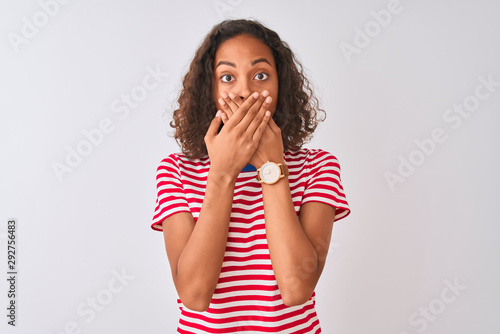 Young brazilian woman wearing red striped t-shirt standing over isolated white background shocked covering mouth with hands for mistake. Secret concept.