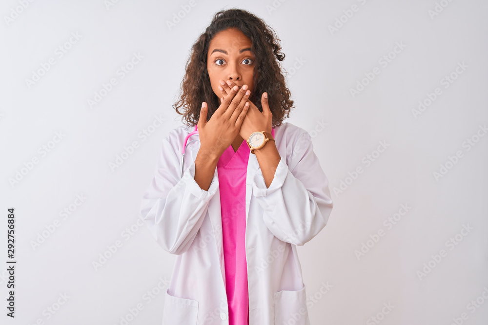 Young brazilian doctor woman wearing stethoscope standing over isolated white background shocked covering mouth with hands for mistake. Secret concept. Young brazilian doctor woman wearing stethoscope standing over isolated white background shocked covering mouth with hands for mistake. Secret concept.