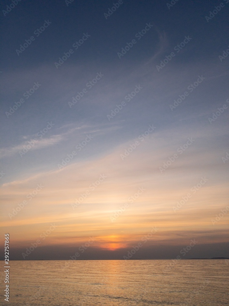 Sunset over quiet sea with sun hiding behind clouds. Crimean seascape copy space