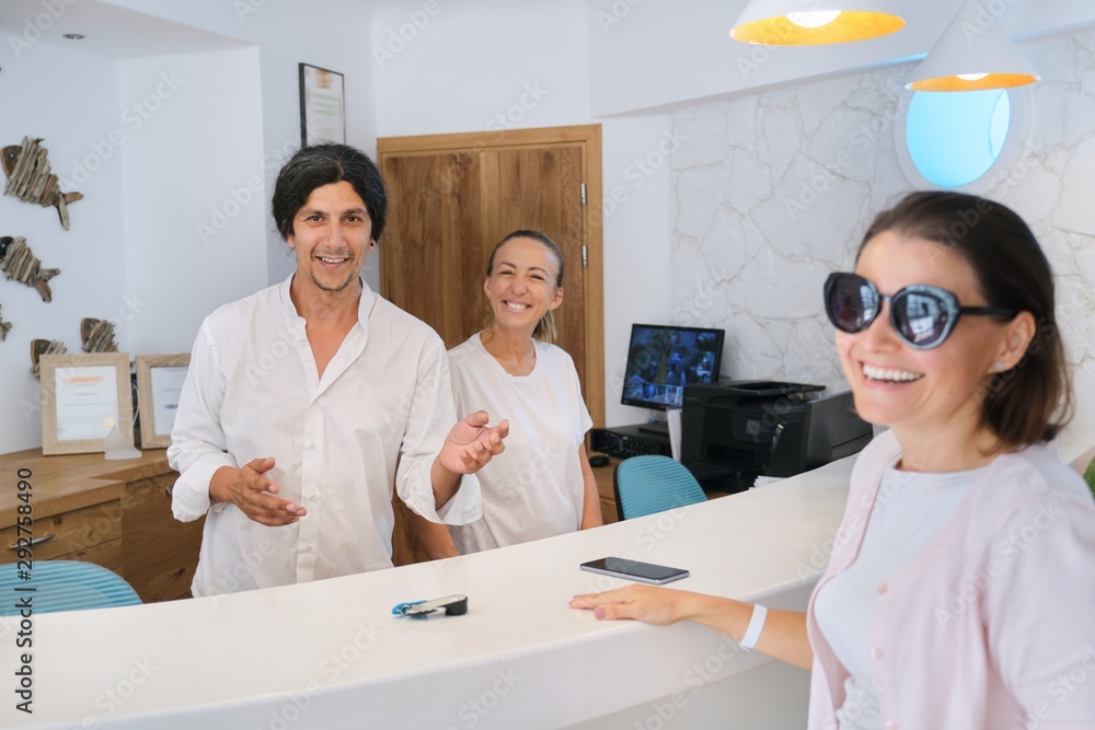 Obraz premium Resort hotel reception and registration of guests. Man and woman receptionists at the workplace