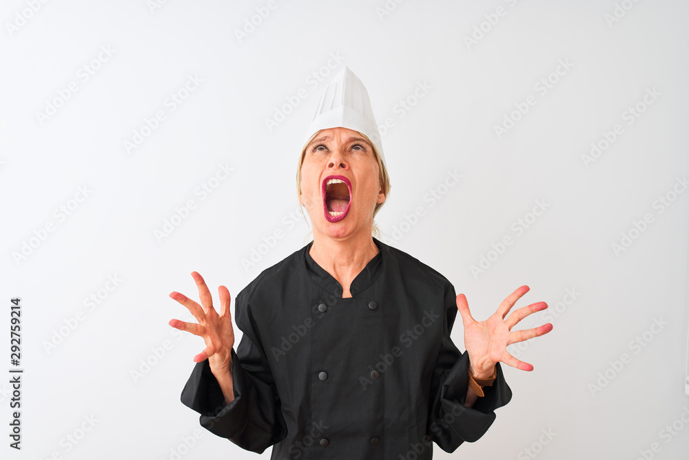 Middle age chef woman wearing uniform and hat standing over isolated white background crazy and mad shouting and yelling with aggressive expression and arms raised. Frustration concept. Middle age chef woman wearing uniform and hat standing over isolated white background crazy and mad shouting and yelling with aggressive expression and arms raised. Frustration concept.