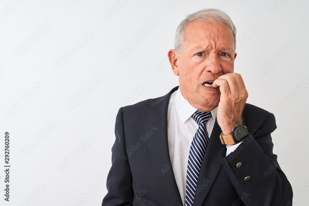 Senior grey-haired businessman wearing suit standing over isolated white background looking stressed and nervous with hands on mouth biting nails. Anxiety problem. Senior grey-haired businessman wearing suit standing over isolated white background looking stressed and nervous with hands on mouth biting nails. Anxiety problem.
