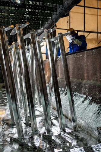 People at work galvanizing metallic structures in a zinc bath photo