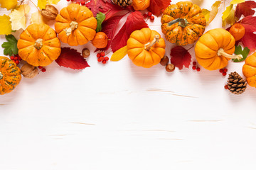 Festive autumn pumpkins decor with fall leaves, berries, nuts on white background. Thanksgiving day or halloween holiday, harvest concept. Top view flat lay composition with copy space for greeting