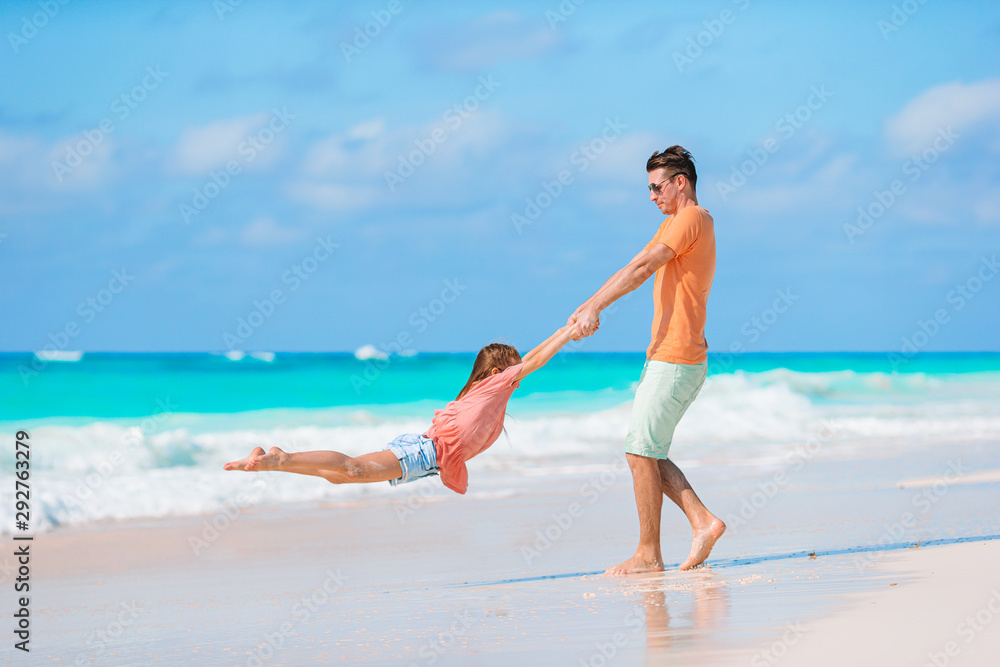 Little girl and happy dad having fun during beach vacation