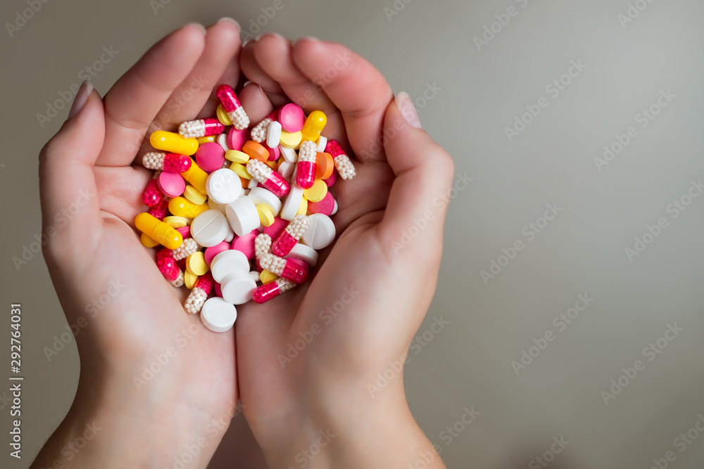 a handful of tablets of different colors in female hands, copy space, close up a handful of tablets of different colors in female hands, copy space, close up