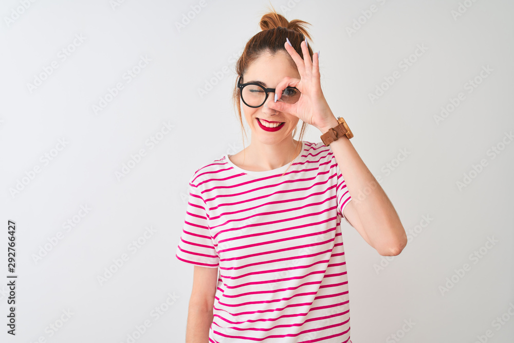 Redhead woman wearing glasses striped t-shirt and pigtail over isolated white background doing ok gesture with hand smiling, eye looking through fingers with happy face. Redhead woman wearing glasses striped t-shirt and pigtail over isolated white background doing ok gesture with hand smiling, eye looking through fingers with happy face.
