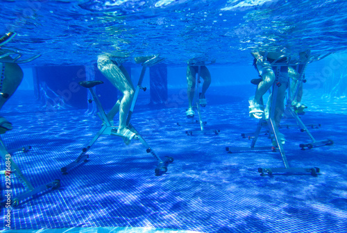 Fitness class doing aqua aerobics on exercise bikes in swimming pool resort hotel © Viktor