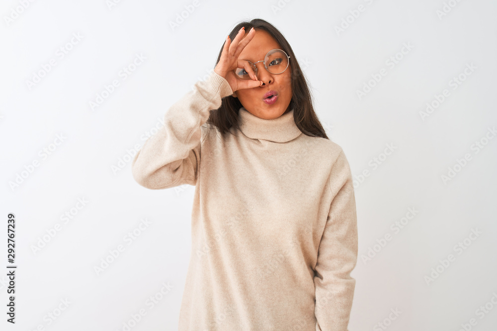 Young chinese woman wearing turtleneck sweater and glasses over isolated white background doing ok gesture shocked with surprised face, eye looking through fingers. Unbelieving expression. Young chinese woman wearing turtleneck sweater and glasses over isolated white background doing ok gesture shocked with surprised face, eye looking through fingers. Unbelieving expression.