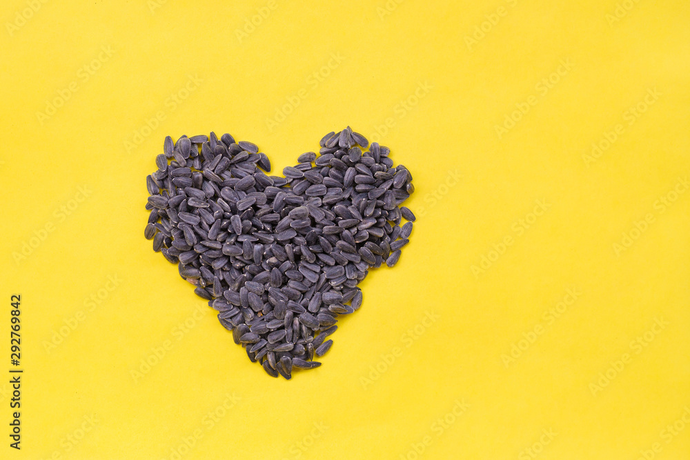 Sunflower seeds in the shape of hearts on yellow background. Flat lay, top view, copy space. Food Concept, harvest time, agriculture. Sunflower seeds in the shape of hearts on yellow background. Flat lay, top view, copy space. Food Concept, harvest time, agriculture.