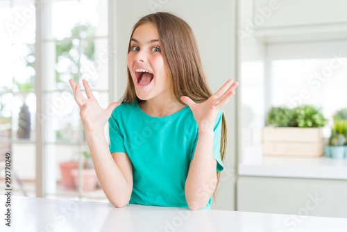 Beautiful young girl kid wearing green t-shirt celebrating crazy and amazed for success with arms raised and open eyes screaming excited. Winner concept