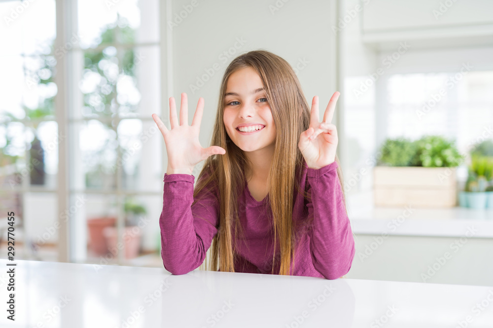 Beautiful young girl kid on white table showing and pointing up with fingers number seven while smiling confident and happy.