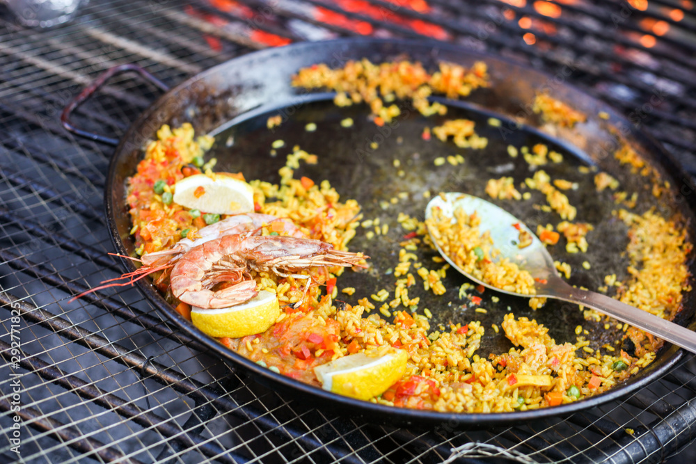 Paella meal with shrimps street food cooked outdoors on the big grill Stock  写真 | Adobe Stock