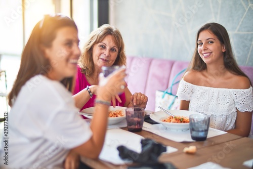 Beautiful group of women sitting at restaurant eating food speaking and smiling