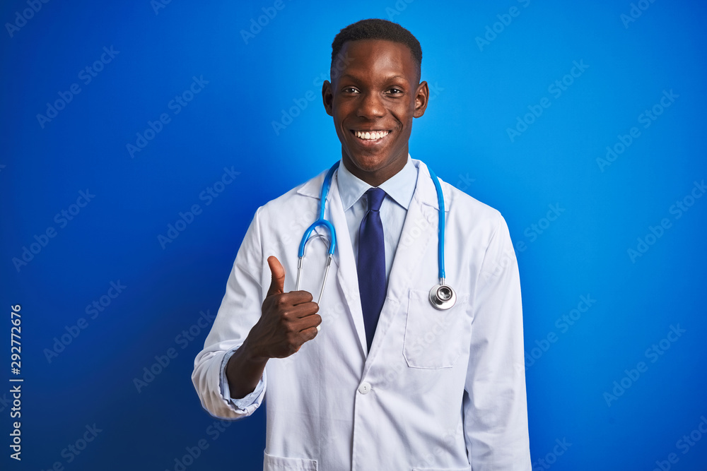 African american doctor man wearing stethoscope standing over isolated blue background doing happy thumbs up gesture with hand. Approving expression looking at the camera with showing success. African american doctor man wearing stethoscope standing over isolated blue background doing happy thumbs up gesture with hand. Approving expression looking at the camera with showing success.