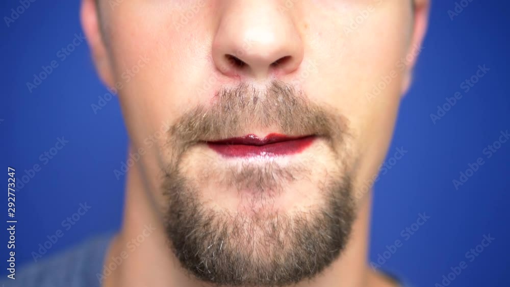 close-up. A bearded man with painted lips licks them sexually. close-up. A bearded man with painted lips licks them sexually.