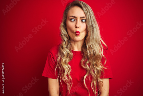 Wallpaper Mural Young beautiful woman wearing basic t-shirt standing over red isolated background making fish face with lips, crazy and comical gesture. Funny expression. Torontodigital.ca