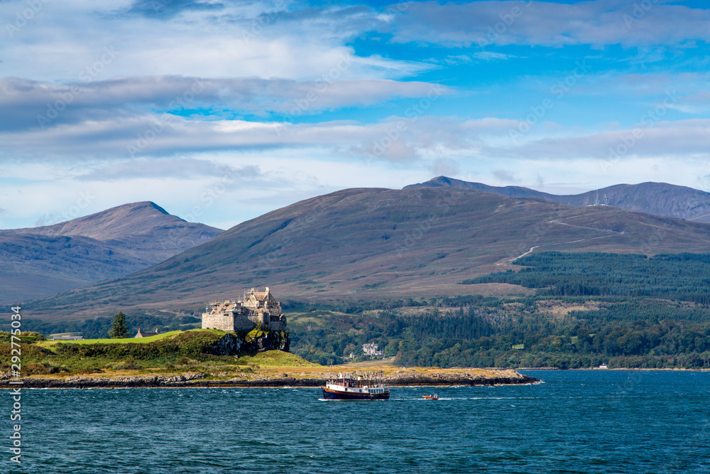 A Small Boat Sails Past Duart Castle on the Shore of Isle of Mull, Scotland