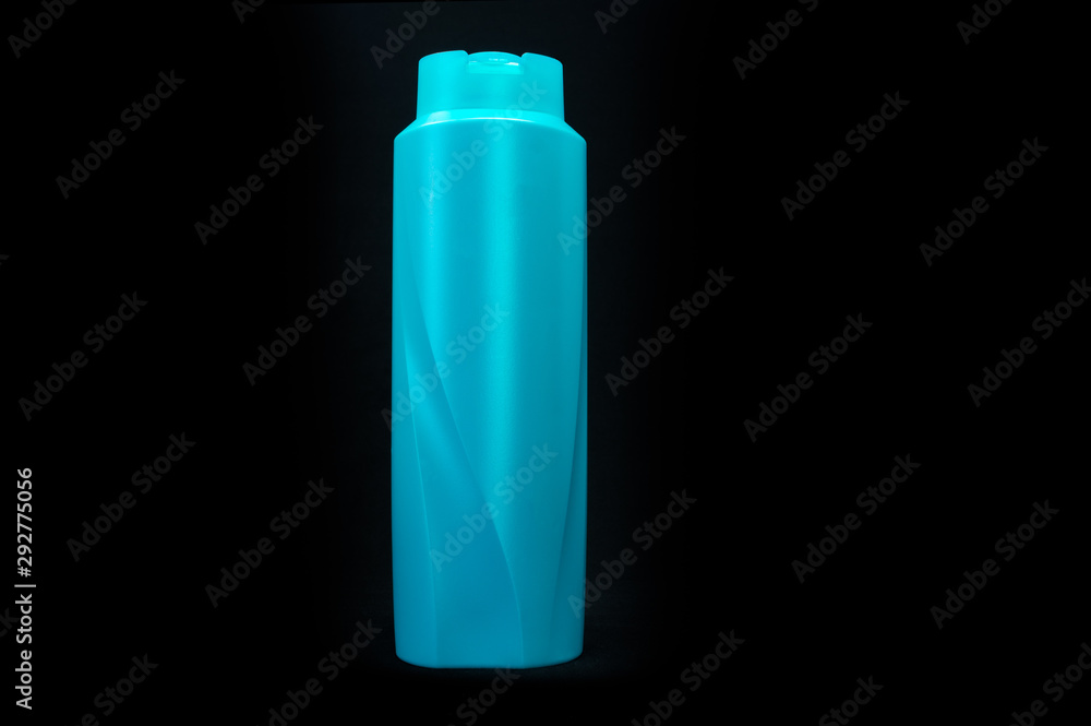 Teal, plastic, shampoo bottle with no labels. Isolated on a black  background. The product cap is closed. Photos | Adobe Stock