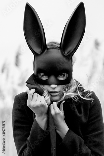 Beautiful blonde woman with scared face in black bunny mask
