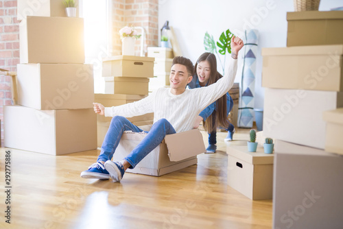 Funny asian couple having fun, riding inside cardboard box smiling happy, very excited moving to a new house © Krakenimages.com