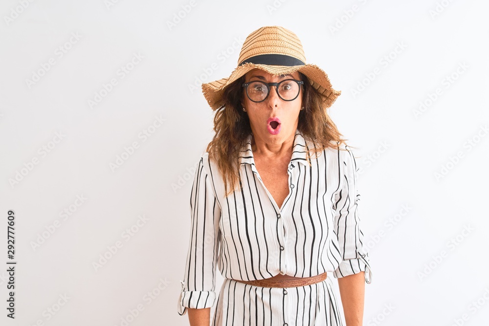 Middle age businesswoman wearing striped dress glasses hat over isolated white background scared in shock with a surprise face, afraid and excited with fear expression Middle age businesswoman wearing striped dress glasses hat over isolated white background scared in shock with a surprise face, afraid and excited with fear expression