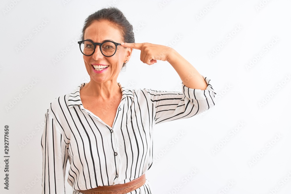 Middle age businesswoman wearing striped dress and glasses over isolated white background Smiling pointing to head with one finger, great idea or thought, good memory