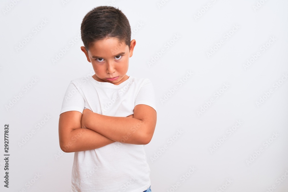 Beautiful kid boy wearing casual t-shirt standing over isolated white background skeptic and nervous, disapproving expression on face with crossed arms. Negative person. Beautiful kid boy wearing casual t-shirt standing over isolated white background skeptic and nervous, disapproving expression on face with crossed arms. Negative person.