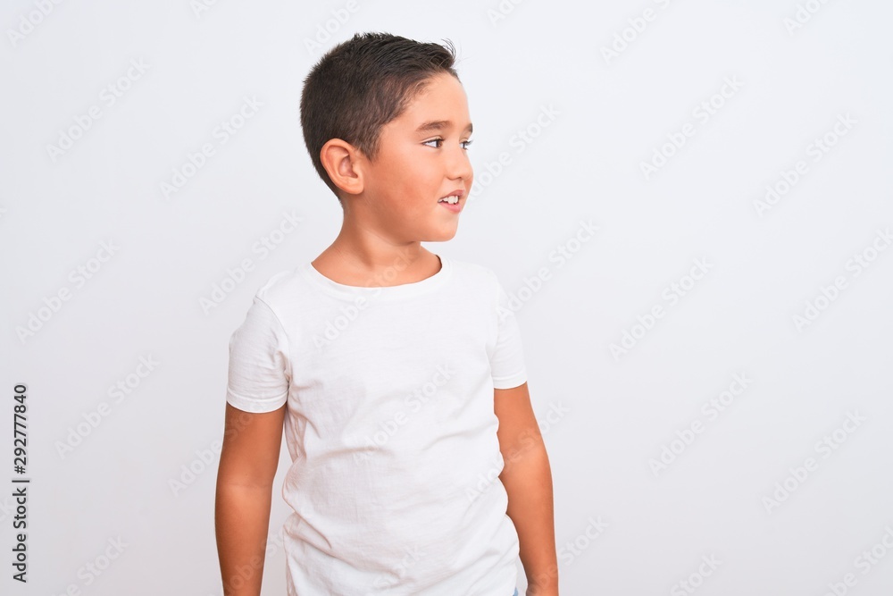 Beautiful kid boy wearing casual t-shirt standing over isolated white background looking away to side with smile on face, natural expression. Laughing confident. Beautiful kid boy wearing casual t-shirt standing over isolated white background looking away to side with smile on face, natural expression. Laughing confident.