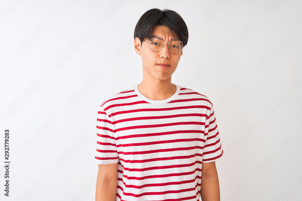 Young chinese man wearing glasses and striped t-shirt standing over isolated white background skeptic and nervous, frowning upset because of problem. Negative person. Young chinese man wearing glasses and striped t-shirt standing over isolated white background skeptic and nervous, frowning upset because of problem. Negative person.