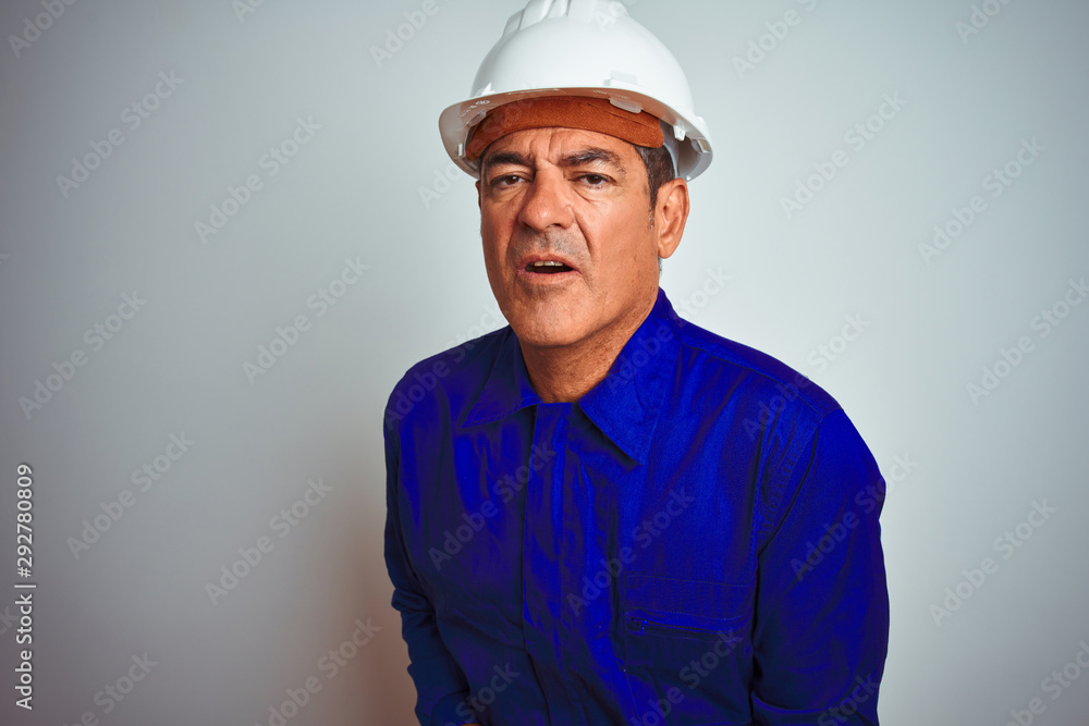 Handsome middle age worker man wearing uniform and helmet over isolated white background with hand on stomach because nausea, painful disease feeling unwell. Ache concept. Handsome middle age worker man wearing uniform and helmet over isolated white background with hand on stomach because nausea, painful disease feeling unwell. Ache concept.