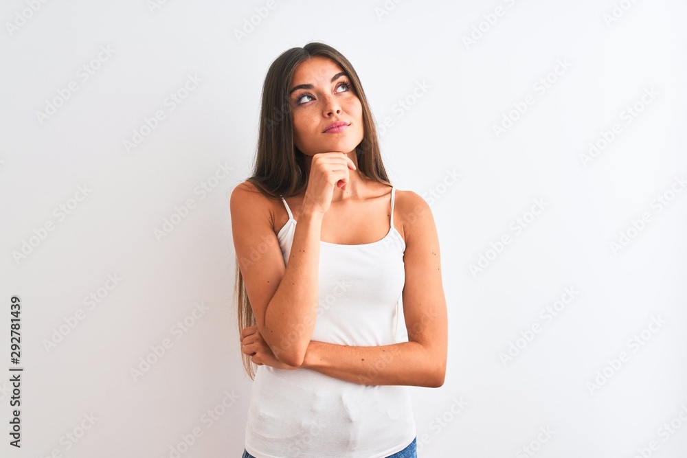 Young beautiful woman wearing casual t-shirt standing over isolated white background with hand on chin thinking about question, pensive expression. Smiling with thoughtful face. Doubt concept. Young beautiful woman wearing casual t-shirt standing over isolated white background with hand on chin thinking about question, pensive expression. Smiling with thoughtful face. Doubt concept.