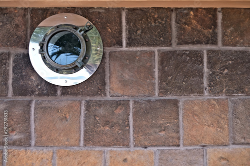 Closed decorative porthole window in a house wall, architecture abstract nautical detail.