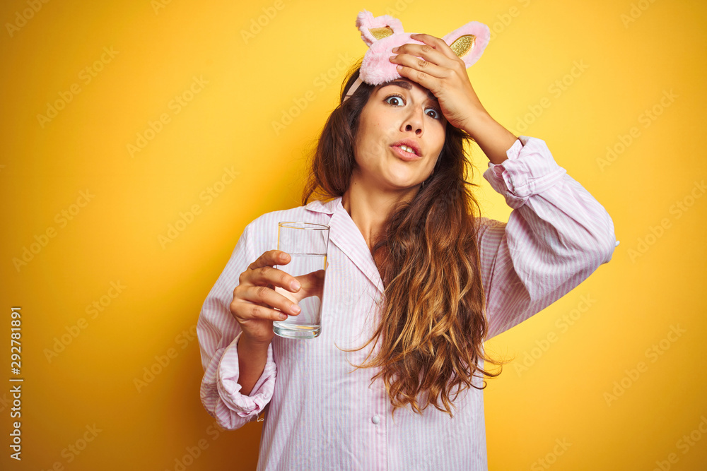 Young woman wearing pajama and sleep mask drinking water over yellow isolated background stressed with hand on head, shocked with shame and surprise face, angry and frustrated Young woman wearing pajama and sleep mask drinking water over yellow isolated background stressed with hand on head, shocked with shame and surprise face, angry and frustrated
