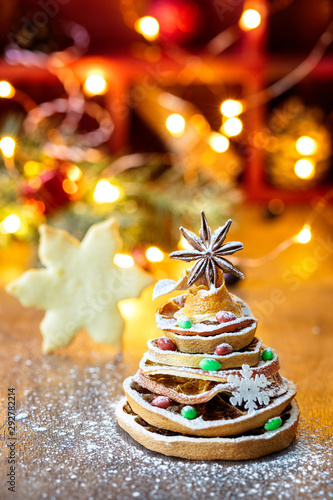 Christmas tree made out of dried orange slices and anise star, with festive light and cookie on background, vertical composition