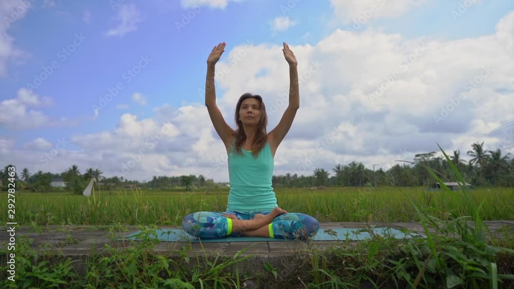 Slowmotion steadicam shot of a young woman doing meditation for Muladhara chakra in a Balinese way Slowmotion steadicam shot of a young woman doing meditation for Muladhara chakra in a Balinese way