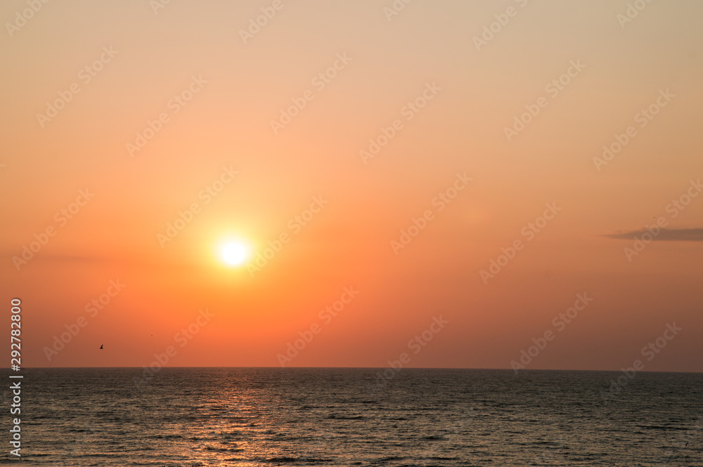 Seascape. Dawn on the beach, orange-red glow in the sky, sun, golden hour. Copy space.
