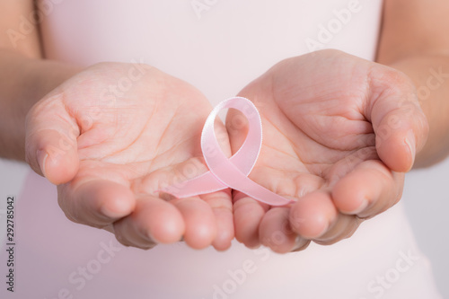 Woman holding a pink ribbon.  Breast cancer awareness month.
