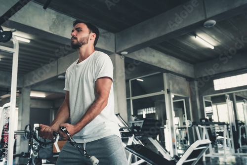 Handsome Man is Exercising With Bodybuilder Pulling Machine in Fitness Club.,Portrait of Strong Sport Man Doing Working Out Muscle Building in Gym., Healthy and Fitness Sport Lifestyle Concept.