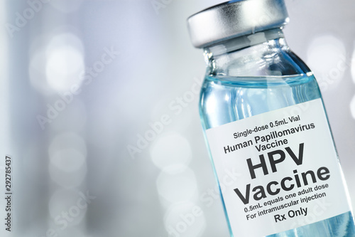 Healthcare concept with a hand in blue medical gloves holding HPV, human papillomavirus, vaccine vial photo