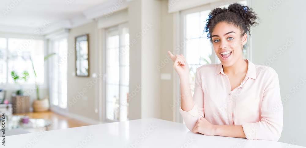 Wide angle of beautiful african american woman with afro hair with a big smile on face, pointing with hand finger to the side looking at the camera. Wide angle of beautiful african american woman with afro hair with a big smile on face, pointing with hand finger to the side looking at the camera.