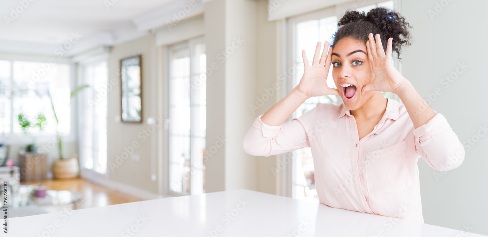 Wide angle of beautiful african american woman with afro hair Smiling cheerful playing peek a boo with hands showing face. Surprised and exited Wide angle of beautiful african american woman with afro hair Smiling cheerful playing peek a boo with hands showing face. Surprised and exited