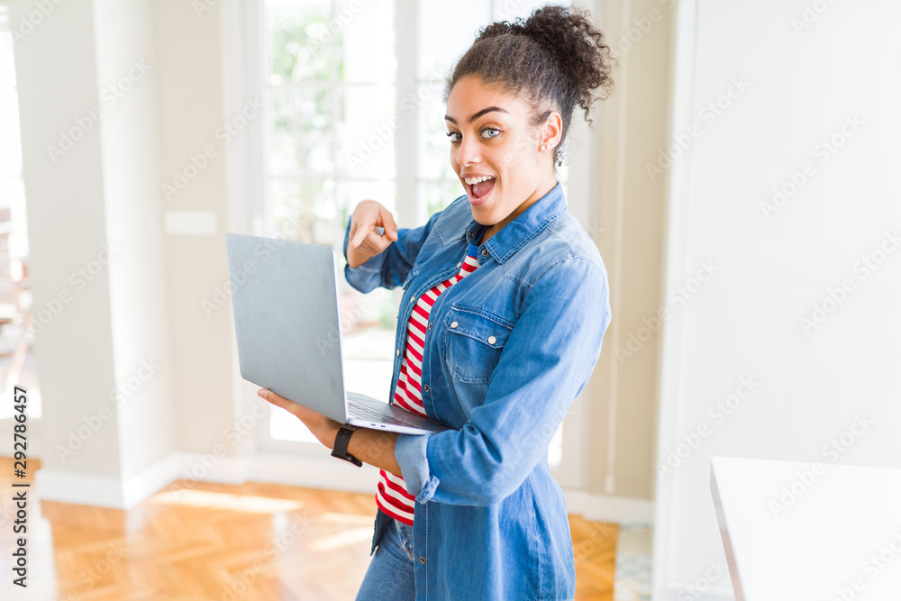 Young african american girl standing working using laptop very happy pointing with hand and finger Young african american girl standing working using laptop very happy pointing with hand and finger