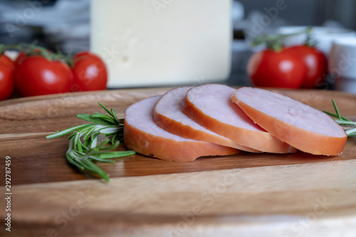 Sliced Canadian Bacon with herbs served on a wooden serving trray