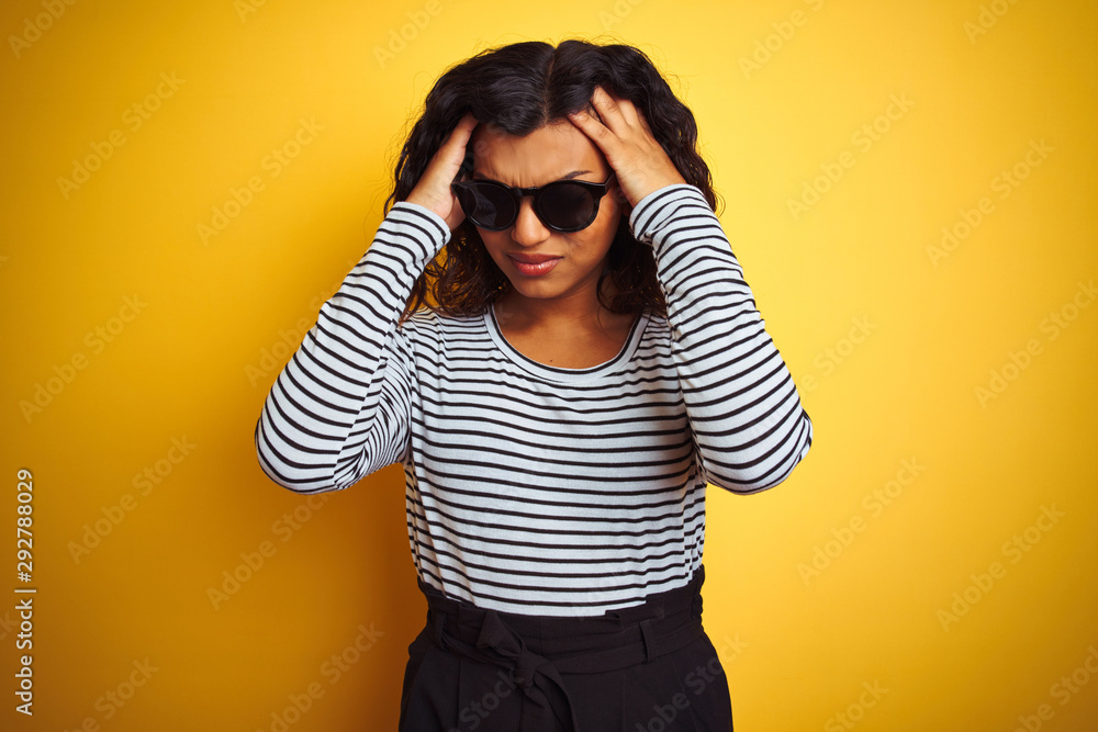 Transsexual transgender woman wearing sunglasses over isolated yellow background suffering from headache desperate and stressed because pain and migraine. Hands on head. Transsexual transgender woman wearing sunglasses over isolated yellow background suffering from headache desperate and stressed because pain and migraine. Hands on head.