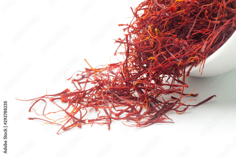 Fototapeta premium Dried saffron dumped from a white ceramic cup. Isolated on white background.