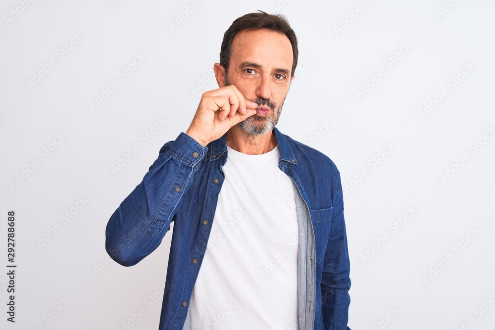 Middle age handsome man wearing blue denim shirt standing over isolated white background mouth and lips shut as zip with fingers. Secret and silent, taboo talking Middle age handsome man wearing blue denim shirt standing over isolated white background mouth and lips shut as zip with fingers. Secret and silent, taboo talking