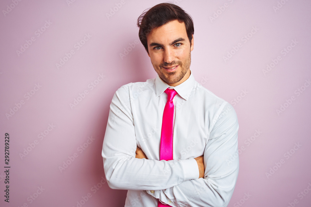 Young handsome businessman wearing shirt and tie standing over isolated pink background happy face smiling with crossed arms looking at the camera. Positive person. Young handsome businessman wearing shirt and tie standing over isolated pink background happy face smiling with crossed arms looking at the camera. Positive person.