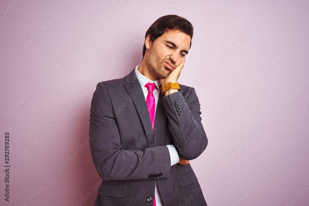 Young handsome businessman wearing suit and tie standing over isolated pink background thinking looking tired and bored with depression problems with crossed arms. Young handsome businessman wearing suit and tie standing over isolated pink background thinking looking tired and bored with depression problems with crossed arms.