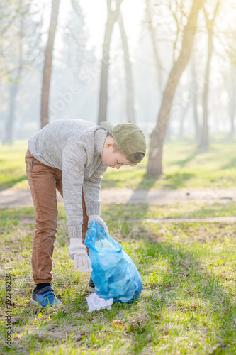 Young boy picking garbage in the summer park. Volunteer and ecology concept